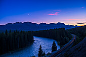 The close conjunction of the waxing crescent Moon near Venus in the evening sky, from the Storm Mountain viewpoint on the Bow Valley Parkway in Banff National Park, Alberta, on July 15, 2018. The mountains to the west define the Continental Divide. The Bow River and the CPR tracks wind off into the distance.