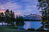 The stars and Mars trailing over Mt. Rundle and Two Jack Lake in Banff National Park, Alberta, on June 3, 2016. Mars is the brightest streak and object in the sky. Note the glitter path of Mars in the water. Satellites streak across the star trails.