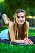 Porträt einer jungen schönen kaukasischen Frau in den 20ern, die in einem Garten im Gras liegt. Lebensstil-Konzept.