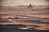 Das Ödland von Bardenas Reales bei Sonnenaufgang mit einer kurvenreichen Straße, die zur Felsformation Castildetierra führt, Navarra, Spanien, Europa