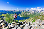 Ein Mann schaut auf den Bergsee von Montespluga, stehend auf Felsen, Madesimo, Valle Spluga, Valtellina, Lombardei, Italien, Europa