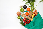 Draufsicht auf frisches Gemüse und Obst in einer Tüte vor weißem Hintergrund
