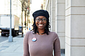 Porträt einer lächelnden Frau mit Abstimmungsknopf in der Stadt