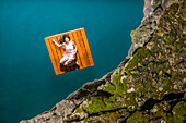 Overhead view of woman lying on floating dock near rocky coast