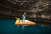 Portrait einer Frau sitzend auf einem Schwimmdock nahe der Felsenküste