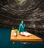 Portrait einer Frau sitzend auf einem Schwimmdock nahe der Felsenküste