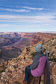 USA, Arizona, Rückansicht einer auf einer Bank sitzenden Touristin im Grand Canyon National Park