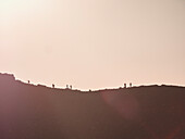 New Zealand, Waikato, Tongariro National Park, Silhouettes of hikers on mountain ridge at sunset