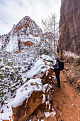 USA, Utah, Springdale, Zion National Park, Ältere Frau beim Wandern in den Bergen im Winter