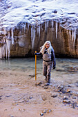 USA, Utah, Springdale, Zion National Park, Ältere Frau überquert Fluss beim Wandern in den Bergen