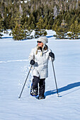 USA, Idaho, Sun Valley, Senior woman wearing snowshoes hiking in mountains