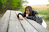 Portrait of teenage girl (16-17) leaning on picnic table