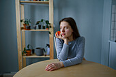 Porträt einer nachdenklichen Frau mit Apfel in der Hand