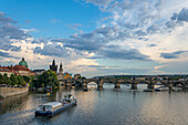 Boat going towards Charles Bridge and Old Town Bridge Tower, UNESCO World Heritage Site, Prague, Bohemia, Czech Republic (Czechia), Europe