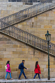 Three Asian tourists walking at staircase at Charles bridge, Old Town, Prague, Czech Republic (Czechia), Europe
