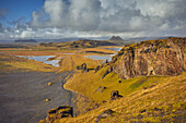 Eine zerklüftete Fels- und Wasserlandschaft um die Insel Dyrholaey, nahe der Stadt Vik, Südisland, Polargebiete