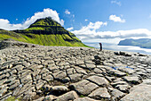 Ein Tourist fotografiert den Berg Skaelingsfjall auf rissigem Boden stehend im Sommer, Streymoy Island, Färöer Inseln, Dänemark, Europa