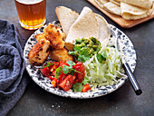 Tacos with cod, cilantro, tomato salad, cabbage, and guacamole