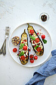 Roasted eggplant halves with garlic, cherry tomatoes, and chili peppers
