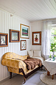 Vintage-Sofa mit Fell und gerahmte Bilder an weißer Holzwand