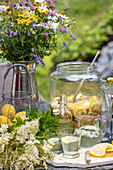 Sommerlicher Tisch im Garten mit Zitronenlimonade und Wildblumenstrauß