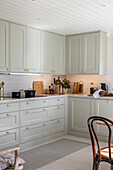Light green kitchen cabinets with gold-colored handles and white ceiling