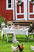 Gedeckter Tisch im ländlichen Stil mit Hühnern im Vorgarten