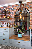 Kitchen unit with brick wall, pendant light and arched window