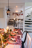 Christmas table setting with candles and fir branches in a white dining room