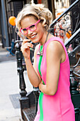 Blonde woman with glasses wearing a pink dress