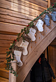 Christmas stockings on wooden staircase banister with fir branch decoration