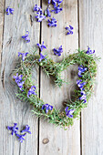 Herzförmiger Kranz mit Hyazinthenblüten (Hyacinthus) auf Holzuntergrund