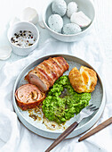Bacon wrapped rabbit roll with mashed peas and fried egg