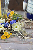 Wreath of grape hyacinths (Muscari), primroses (Primula veris), primroses and hay