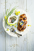 Easter plait with eggshell filled with primrose and forget-me-not, Easter eggs in an Easter bag and cutlery