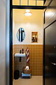 Small guest bath with orange-brown tiles and wall mirror