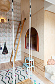 Children's room with loft bed made of light-colored wood and a swing