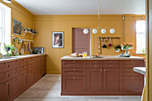 Spacious kitchen with mustard yellow wood paneling and terracotta-colored cabinets