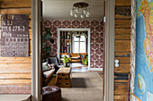 View through door frame into cozy living room with vintage furniture and patterned wallpaper