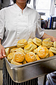 Baker holding a tray of freshly baked scones