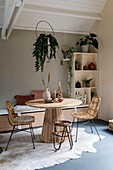 Essbereich mit rundem Holztisch, Rattanstühlen und Zimmerpflanzen