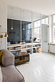 Bright study with glass partition wall and vintage chest as a coffee table