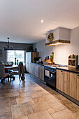 Open-plan kitchen with dining area, modern wooden cupboards and stone tiles