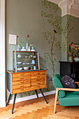 Vintage table with ceramic collection in front of green-painted wall with tree motif