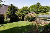 Large garden with greenhouse and manicured lawn in spring