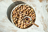 Organic pistachio nuts in the ceramic bowl on rustic wooden table