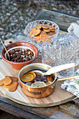 Wooden tray with punch in a copper pot, biscuits and nuts, outdoors