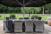 Terrace with rattan dining table, chairs and large parasol