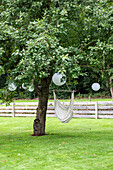 Hanging chairs and white lanterns on a tree in the garden