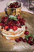 Sponge cake with fresh cherries, strawberries and redcurrants on a golden platter